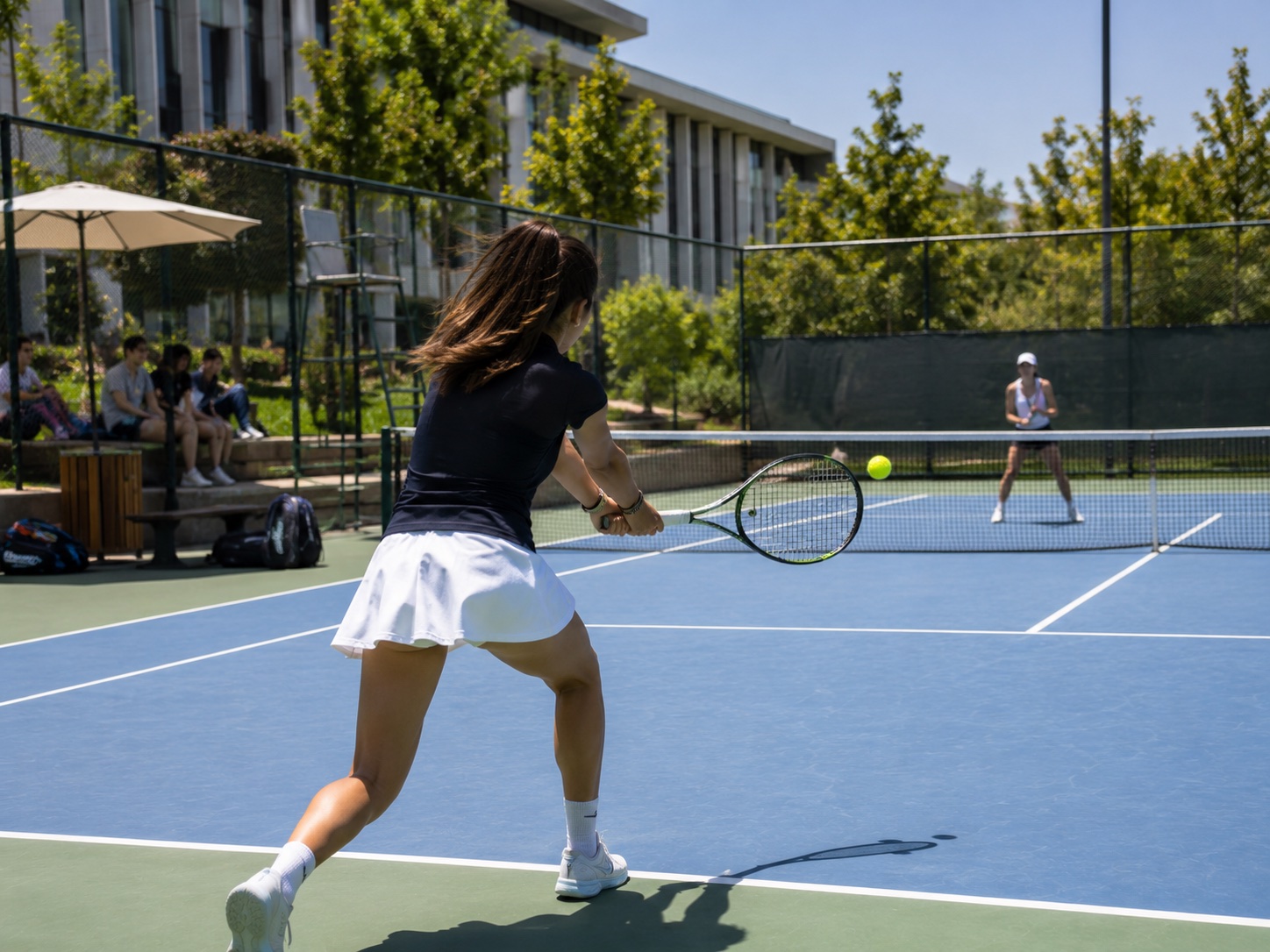 Kampüs kortunda tenis oynayan iki öğrenci